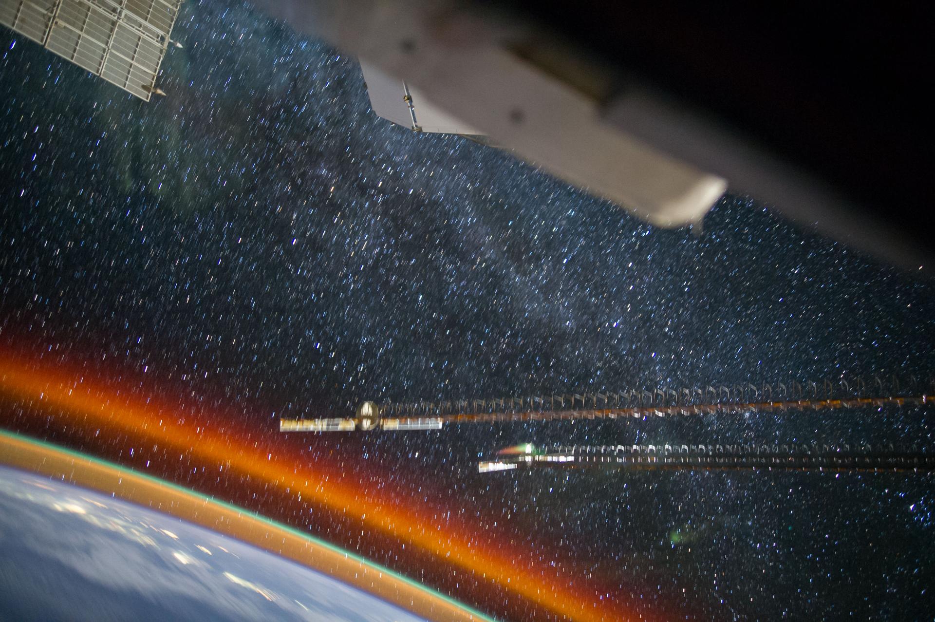 The Milky Way above a band of orange airglow, photographed from the International Space Station